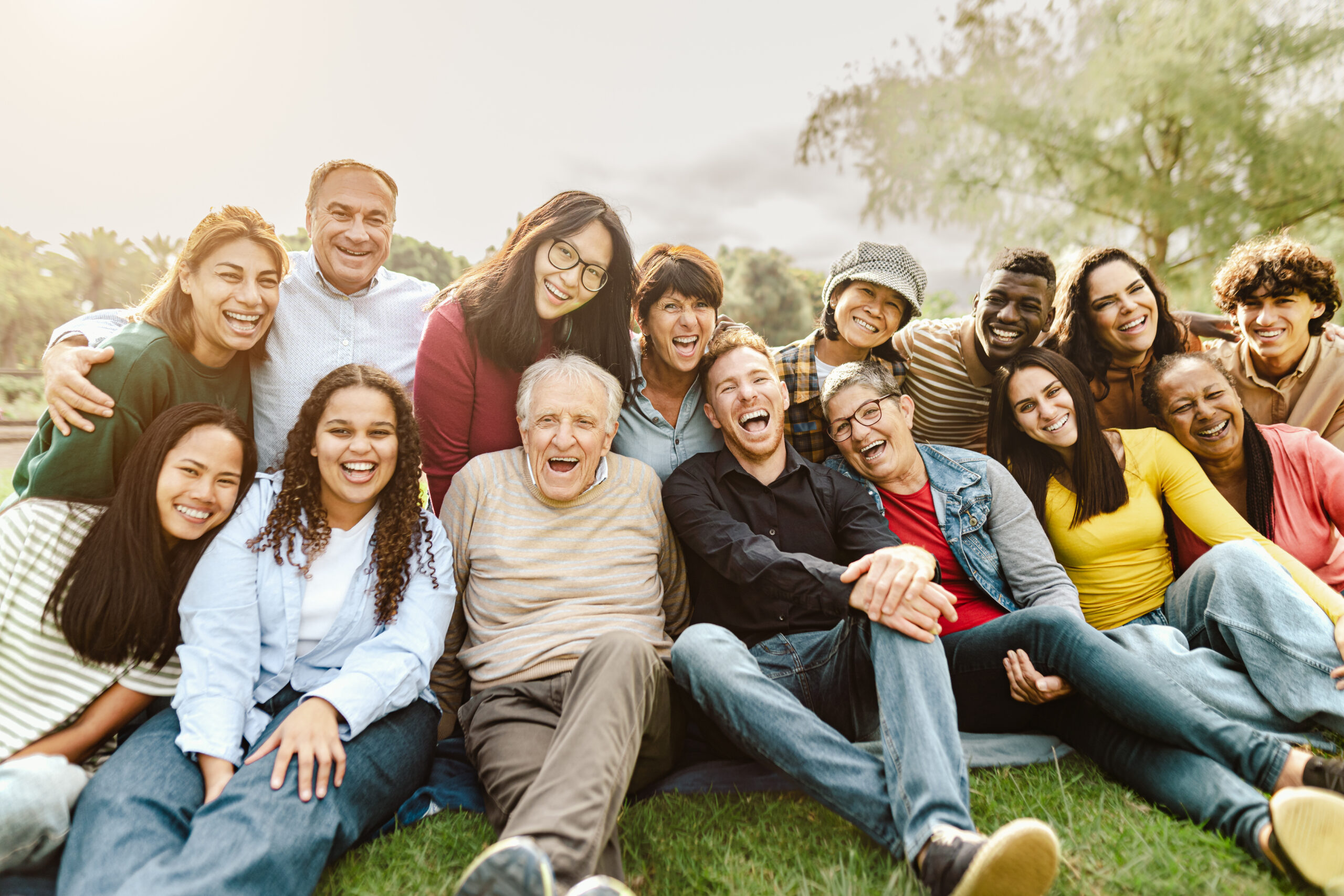 Happy multigenerational people having fun sitting on grass in a